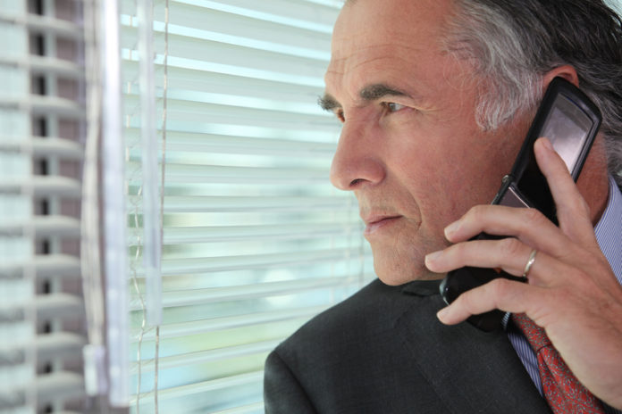 Man peering through some blinds