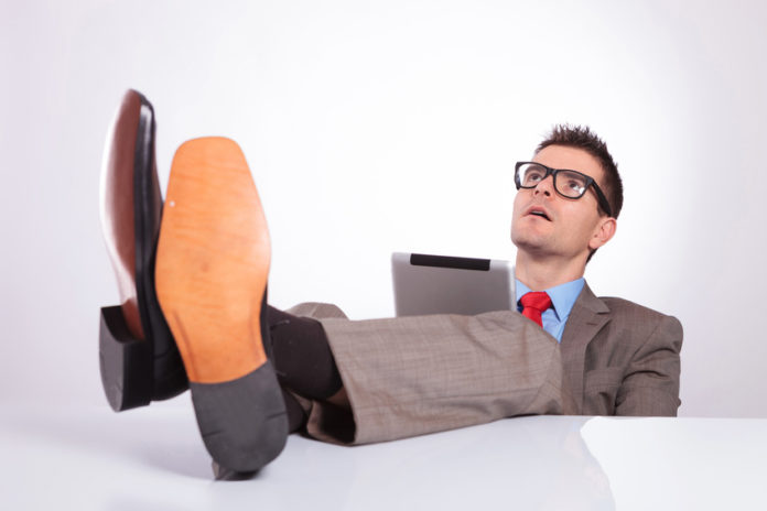 young business man looks up with feet on desk