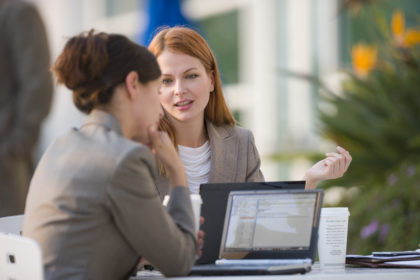 Two businesswomen with laptops working in cafe