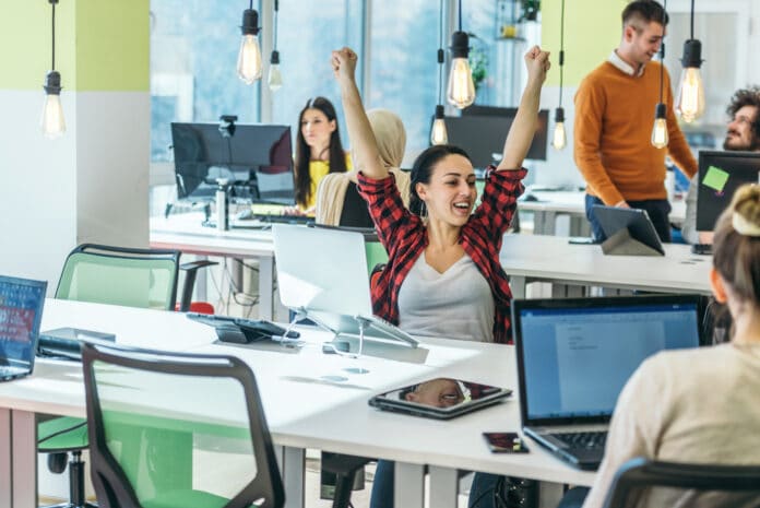 Happy employee cheering while lifting her hands high in the air bien-être et engagement -CreditPhoto-Depositphotos-CadreDirigeantMag2022.jpg